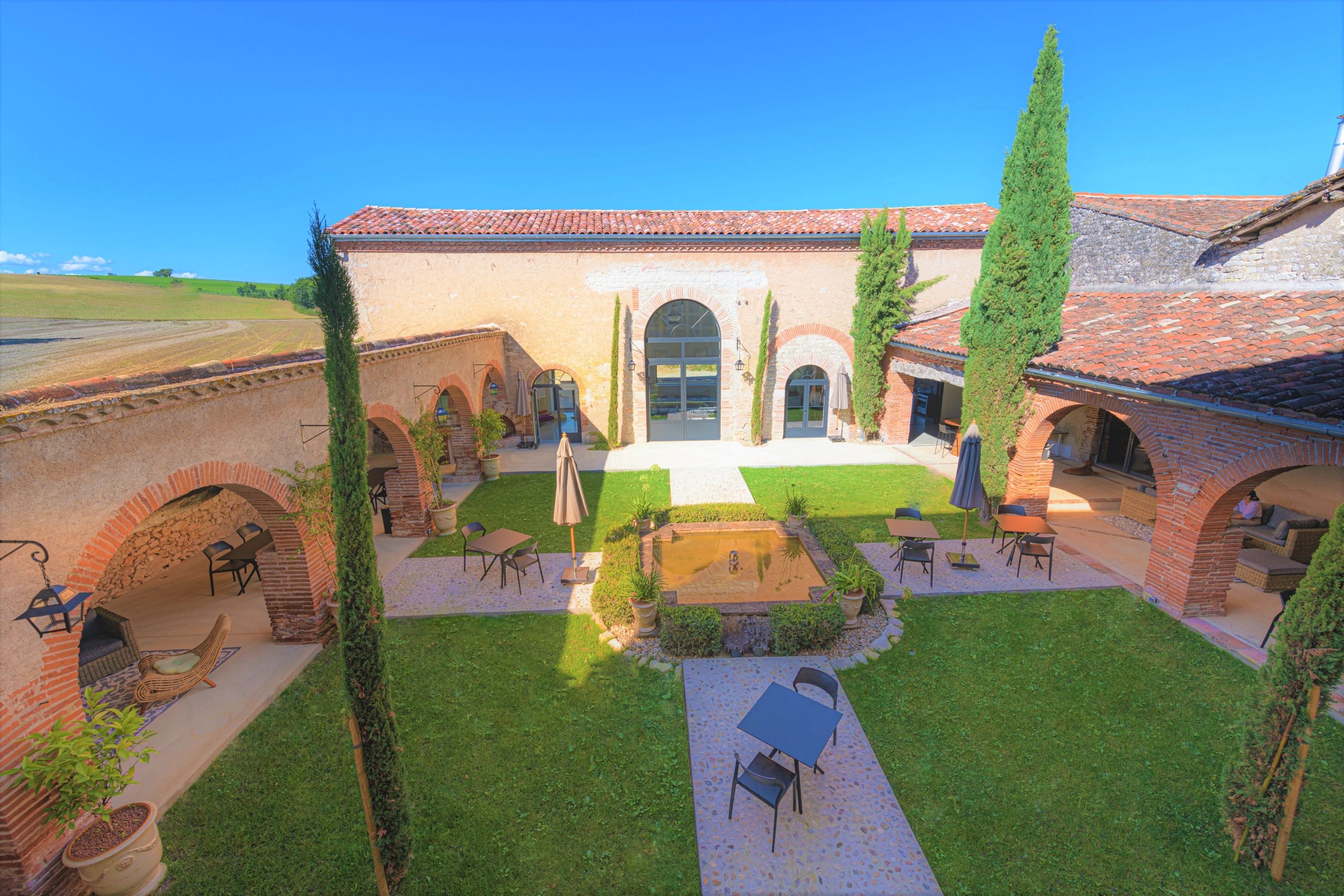 Un patio ensoleillé entouré de murs de pierre et de verdure, offrant une atmosphère paisible et chaleureuse dans un cadre idyllique, proche de Toulouse.